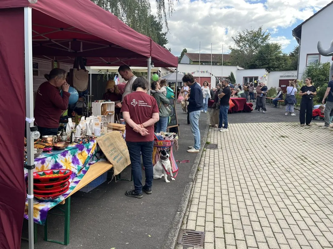 Ehrenamtliche in TERRA-Shirts betreuen einen Verkaufsstand mit Waren und Informationsmaterial.